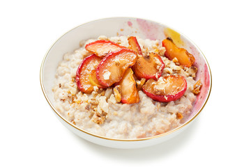 Oat porridge with caramelized apples and nuts isolated on white background