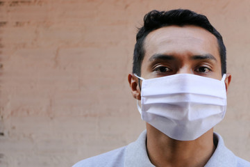 Young Latino man in a medical mask. Close-up of a man wearing a mask to protect himself against...