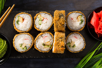 Set of fried sushi rolls with wasabi and ginger on a black background. Japanese oriental cuisine