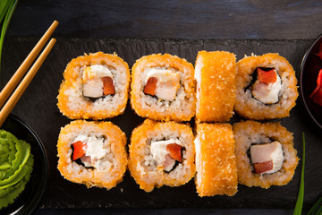 Set of fried sushi rolls with wasabi and ginger on a black background. Japanese oriental cuisine
