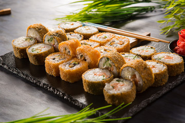 Set of fried sushi rolls with wasabi and ginger on a black background. Japanese oriental cuisine