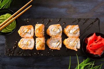 Set of fried sushi rolls with wasabi and ginger on a black background. Japanese oriental cuisine