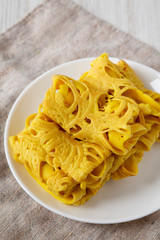 Homemade Net Crepe Roti Jala on a white plate, side view. Close-up.