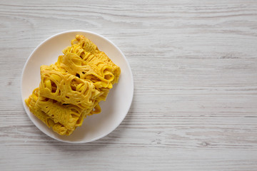 Homemade Net Crepe Roti Jala on a white plate on a white wooden background, top view. Flat lay, overhead, from above. Copy space.
