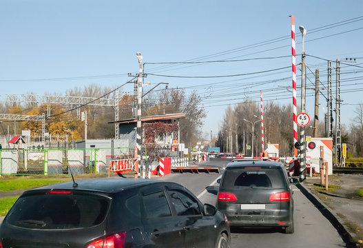 Cars in front of a railway crossing are stopped by raised barriers of protective devices on the road