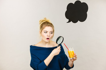 Woman holding magnifying glass investigating juice
