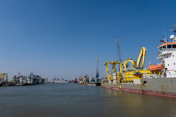 Huge cranes and ships anchored at harbor. International commercial port, city of Rotterdam background. Logistics business