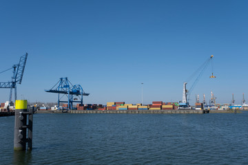 Huge cranes and ships anchored at harbor. International commercial port, city of Rotterdam background. Logistics business