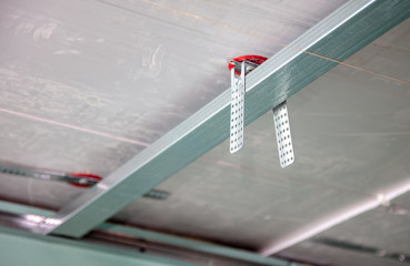Worker fastens a metal profile to the ceiling.