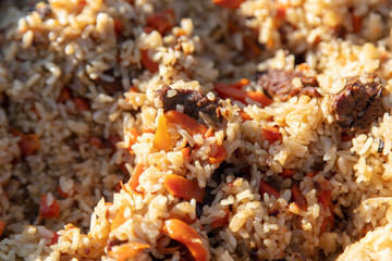 Pilaf with rice is cooked on a cast-iron cauldron.