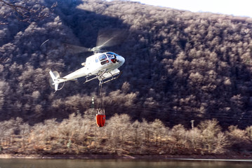 helikopter bekämpft einen Waldbrand mit wasser vom see © G_T_K_