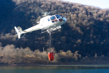 helikopter bekämpft einen Waldbrand mit wasser vom see © G_T_K_
