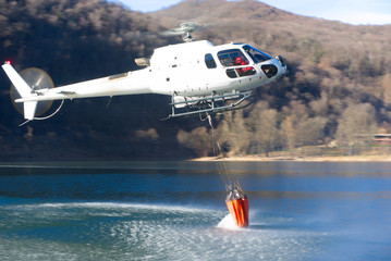 helikopter bekämpft einen Waldbrand mit wasser vom see