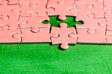 the unexpected solution. pink puzzle with one piece at wrong position, on a green background,...