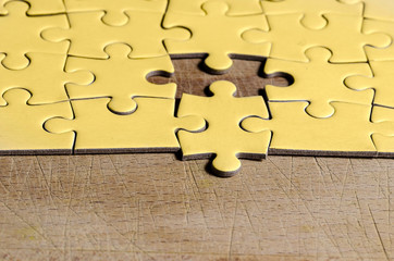 the unexpected solution, yellow puzzle with one piece at wrong position, on wooden table , symbol...