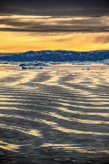 Glacier Ice floating on the water, iceberg in greenland on sunset.