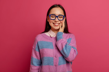 Young charming Asian woman touches cheek gently, feels very happy after passing exam or getting...