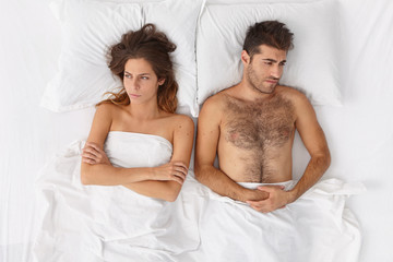 Unhappy woman and man lie apart in bed, dont speak to each other and have problems in...