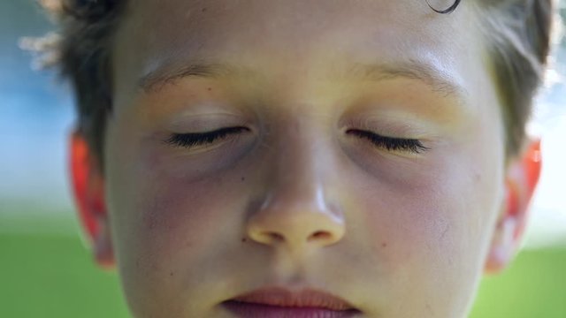 Young boy face turning head to camera portrait close-up eyes closing in meditation and contemplation