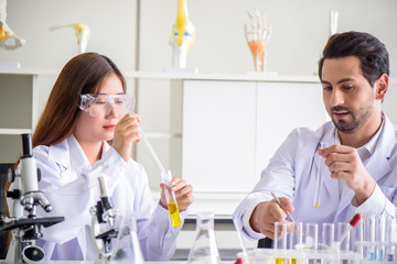 Attractive happiness scientist lab technician assistant analyzing sample in test tube at laboratory. Medical, pharmaceutical and scientific research and development concept.