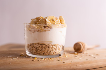Yogurt with oats, banana and honey on wooden table. Healthy and nutritious snack.