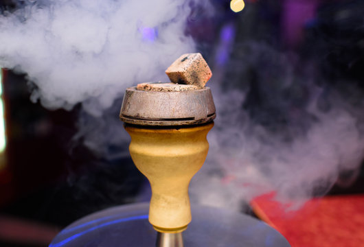 The top of a smoky and delicious hookah. A hookahman is preparing a hookah for restaurant guests.