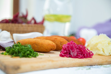Ukrainian tradition food on a wooden board . Red cabbage sauerkraut in a small bowl . mashed potatoes . Mayonnaise, Garlic, Onion, Tomatoes. Chopped coriander.Chicken Kiev cutlets with parsley leaves.