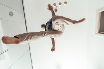 A young man performing parkour from his home, photographed from below