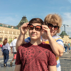 On a bright summer day, mom puts on beautiful sunglasses on her son