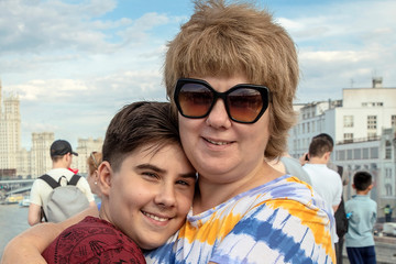 On a bright summer day, mom hugs her son