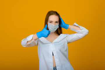 The caucasian girl in blue colored protective face mask. The girl looking at camera. Portrait shot over yellow background. virus and pollution protection concept.