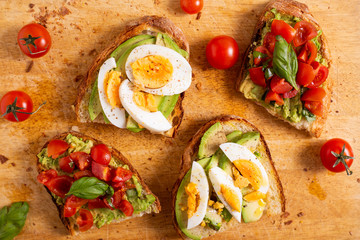 Mixed avocado toast with boiled eggs and tomatoes. Ideas for fast and nutritious dish. Summer food.