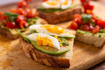 Mixed avocado toast with boiled eggs and tomatoes. Ideas for fast and nutritious dish. Summer food.