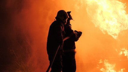 Rear view of Asian fireman wear fire protection suit. Firefighter spray water fighting. Emergency,...