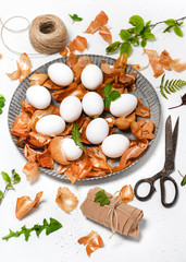 Preparation of Easter eggs for dyeing with onion peels and pattern of fresh leaves. Natural ecological staining with food coloring. Selective focus.