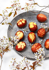 Homemade Easter eggs in a rustic metal plate with wild white flowers of serviceberry tree. (Amelanchier). Selective focus.