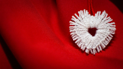 Beautiful white heart made of white thread on a red background