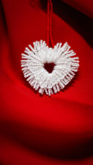 Beautiful white heart made of white thread on a red background