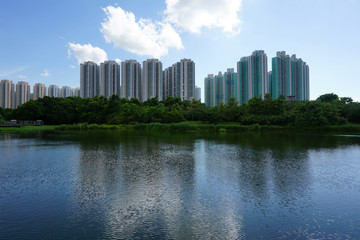 Fototapeta na wymiar scenic view of city skyline, buildings reflected in water in Hong Kong wetland park