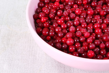 Frozen cranberry in pink plate on linen tablecloth