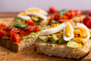 Mixed avocado toast with boiled eggs and tomatoes. Ideas for fast and nutritious dish. Summer food.