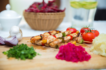 Set of Shish Kebabs . beef kebab on a wooden board . Red cabbage sauerkraut . mashed potatoes . Garlic, Onion, Tomatoes. Chopped coriander . Lamb kebab on a wooden skewer .