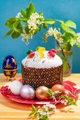 bird cherry branch next to easter cake and colorful easter eggs on wooden table