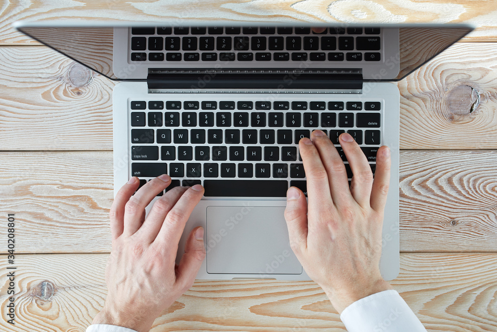 Aufkleber top view of man's hands typing on laptop in sunny day. coworking or working at home concept image.