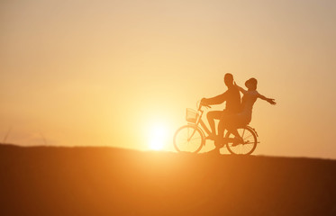 silhouette of couple driving bike happy time sunset