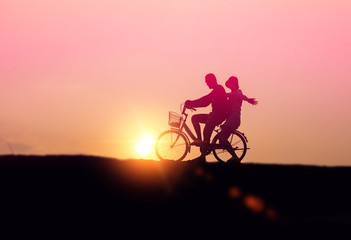 silhouette of couple driving bike happy time sunset