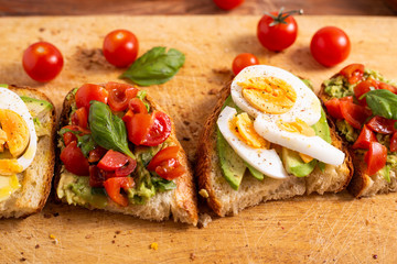 Mixed avocado toast with boiled eggs and tomatoes. Ideas for fast and nutritious dish. Summer food.