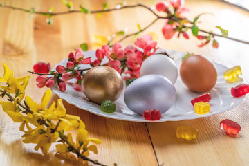 multicolored Easter eggs and branch with flowers on wooden table
