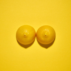Two yellow lemons on a bright yellow background, imitation of a beautiful female breast.
