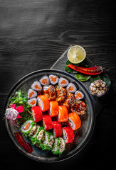 set of sushi roll with salmon, avocado, cream cheese, cucumber, rice, caviar, eel in plate on black wooden table background